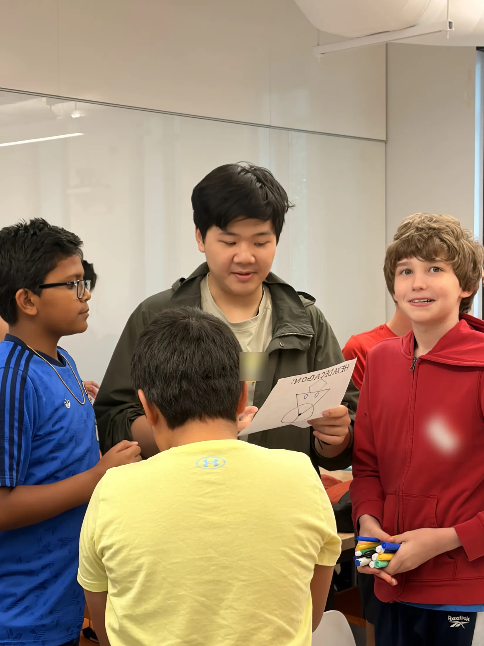 A university mentor reads a student's drawing aloud while students gather round