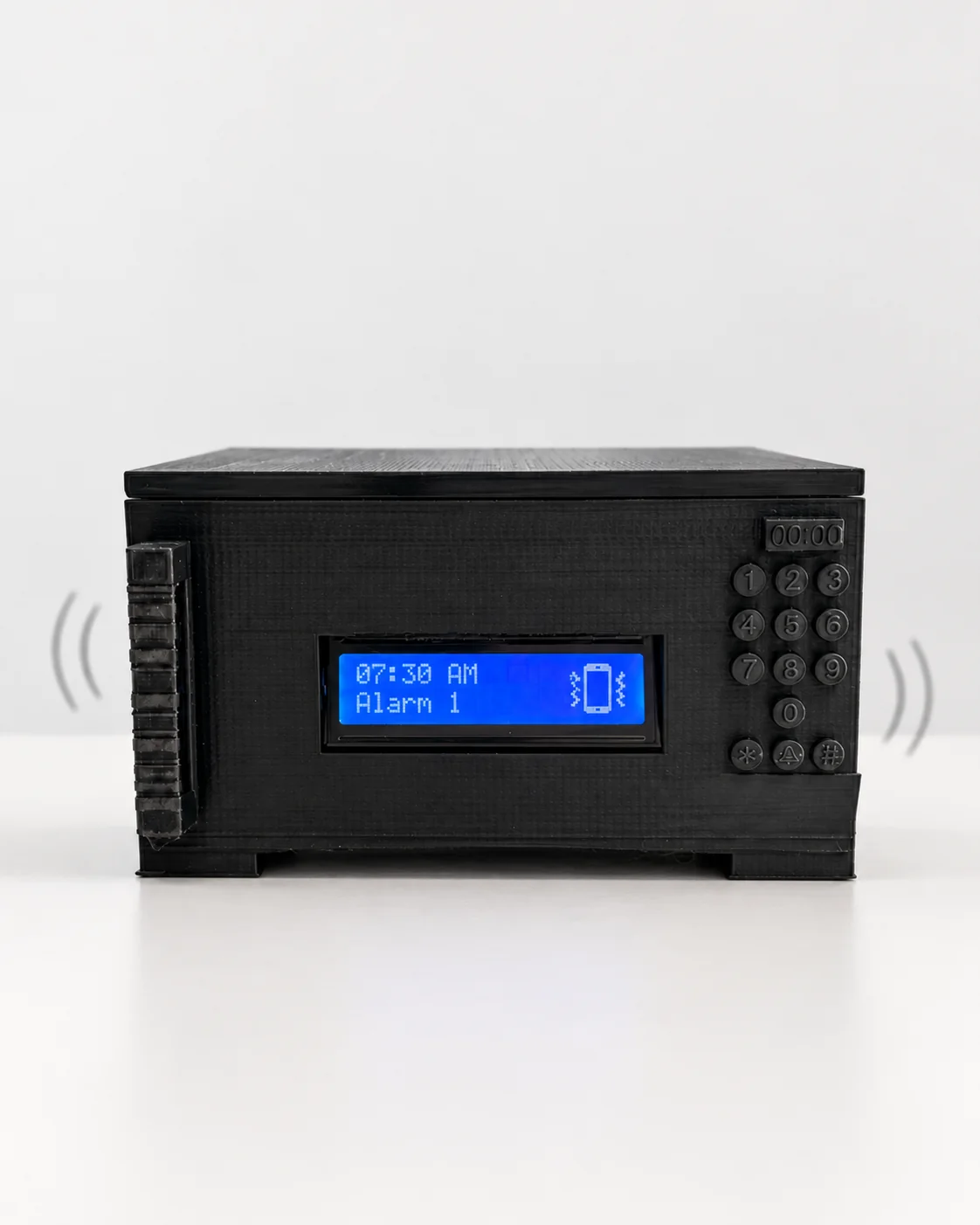A black 3D-printed alarm clock with a keypad, its screen showing a vibrating alarm